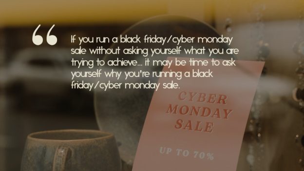 A sign in a store window advertises a cyber monday sale next to ceramic ware, with the quote: "If you run a black friday/cyber monday sale without asking yourself what you are trying to achieve... it may be time to ask yourself why you're running a black friday/cyber monday sale."
